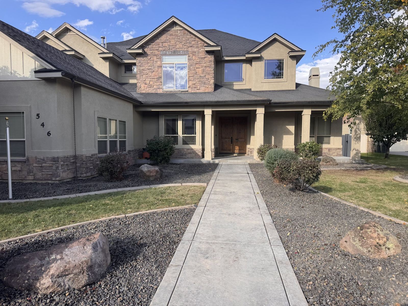 Stone-faced two-story home with new stamped concrete walkway and clean front-yard landscaping